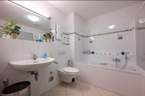 ein weißes Badezimmer mit einem Waschbecken, einem WC und einer Badewanne in der Unterkunft Wohnwerk: Penthouse - Moselblick in Traben-Trarbach