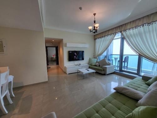 a large living room with a couch and a tv at Beachfront Holiday Homes in Ajman 