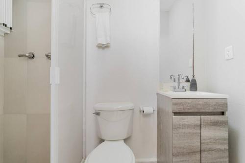 a white bathroom with a toilet and a sink at REEF Beachfront 3BDR apartment by CASA PARAISO in Cancún