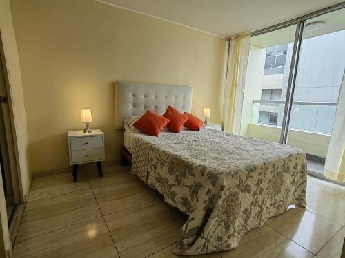 Un dormitorio con una cama con almohadas rojas y una ventana en Romántico departamento con Vista al Mar, en Lima