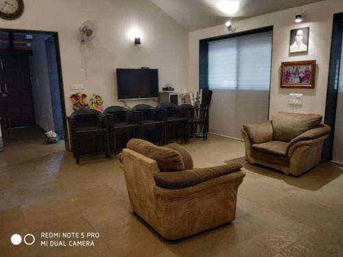 een woonkamer met 2 stoelen en een televisie bij Forest Feels in Nashik