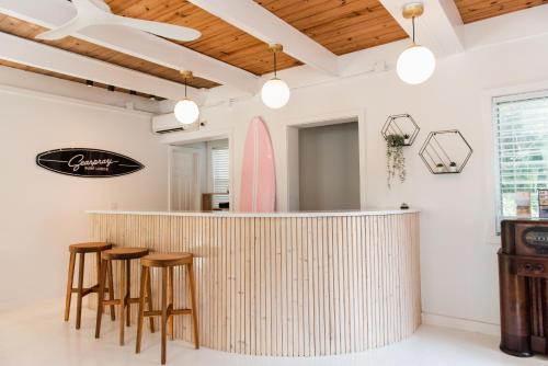 a bar with wooden stools and a surfboard on the wall at Seaspray Surf Lodge in Vero Beach