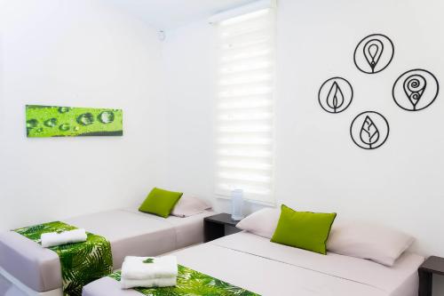 a room with two white beds and green pillows at Casas Campestres Los Miradores de Fruworld in Carmen de Apicalá