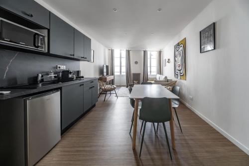 a kitchen with black cabinets and a table and chairs at Résidence Aristide Briand - Appartements en Centre Ville in Vichy