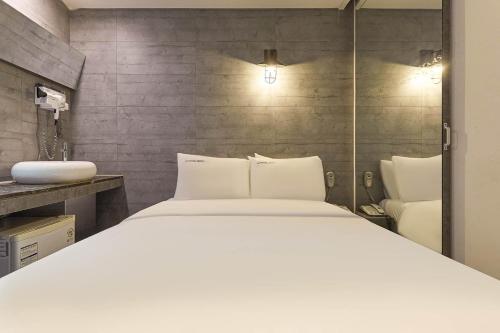 um quarto com uma cama branca e um lavatório em HERTZ Hotel em Seul