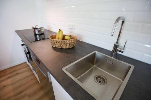 a kitchen counter with a sink and a basket of fruit at Ganzes Apartment -London- in Erftstadt - 3 Zimmer & 63qm - nahe Köln, Messe, Phantasialand & Bonn - Familienurlaub oder Business Trip in Erftstadt