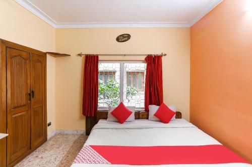 a bedroom with a bed and a window with red curtains at OYO Flagship 81283 Sukhsagar in Gurgaon