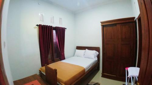 a small bedroom with a bed and a wooden cabinet at Eltanin Homestay by FH Stay in Salakan