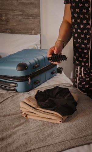 a woman is playing with a suitcase on a bed at Hotel StayHome in Ensenada