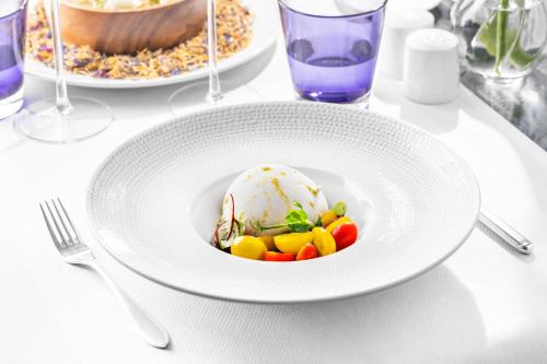 a white plate with ice cream and vegetables on a table at Palácio Estoril Hotel, Golf & Wellness in Estoril