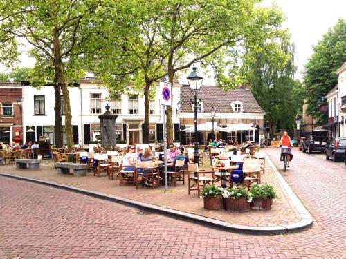 a group of people sitting at tables on a street at Cottage Markdal in Breda