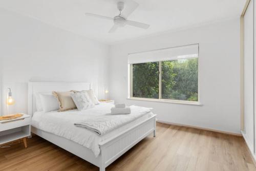 a white bedroom with a bed and a window at Seymour Cottage in Victor Harbour in Victor Harbor