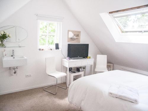 a bedroom with a bed and a desk with a television at Cottage Markdal in Breda