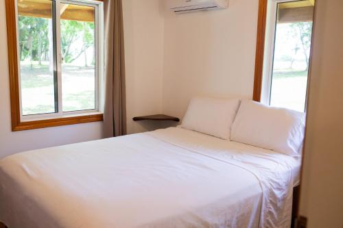 a white bed in a room with two windows at Crystal Creek Lodge in Orange Walk