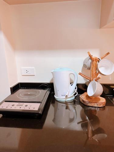 a counter top with a laptop and cups on a table at Luxury Suites at Brenthill Baguio City in Baguio
