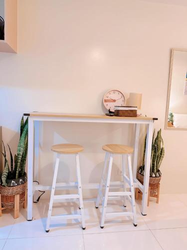 a desk with two stools and a clock on a wall at Luxury Suites at Brenthill Baguio City in Baguio