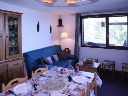 un salon avec une table et un canapé bleu dans l'établissement Grand appart 6 pers avec balcon, wifi et superbe vue - FR-1-322-532, aux Orres