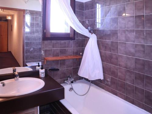 une salle de bain avec un lavabo et une baignoire et un lavabo dans l'établissement Grand appart 6 pers avec balcon, wifi et superbe vue - FR-1-322-532, aux Orres