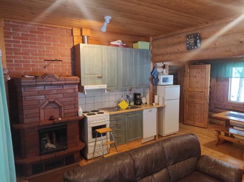 cocina con fogones y sofá en una habitación en Kalliorinteen Mökit Havupirtti en Töysä