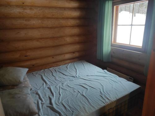 uma cama num chalé de madeira com uma janela em Kalliorinteen Mökit Havupirtti em Töysä