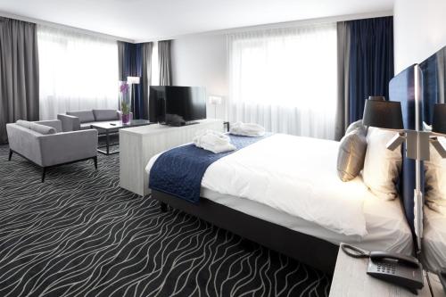 
a hotel room with two beds and a desk at Van der Valk Hotel Mons Congres in Mons
