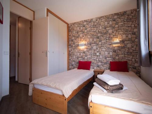 two beds in a room with a stone wall at Appartement Valmorel, 2 pièces, 4 personnes - FR-1-291-895 in Valmorel