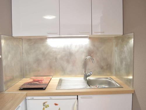 - une cuisine avec un évier et des placards blancs dans l'établissement Appartement T2 avec Piscine, 4 Couchages, Proche Plage - Narbonne Plage - FR-1-229B-97, à Narbonne