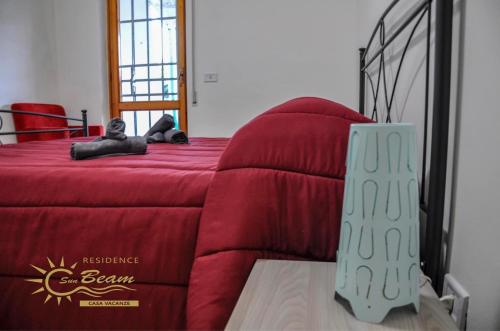 a bedroom with a red bed with a red blanket at Residence Sunbeam in Leporano Marina