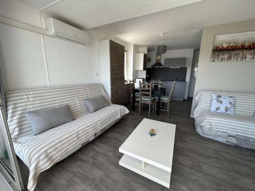 un salon avec un canapé et une table dans l'établissement T2 Cabine Climatisé 6 Couchages avec Parking - Port Camargue - FR-1-250-260, au Grau-du-Roi