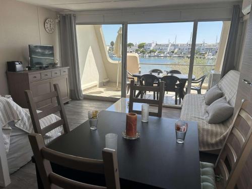 un salon avec une table et des chaises et un balcon dans l'établissement T2 Cabine Climatisé 6 Couchages avec Parking - Port Camargue - FR-1-250-260, au Grau-du-Roi