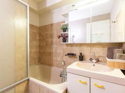 une salle de bain avec une baignoire, un lavabo et un miroir dans l'établissement Appartement pour 4 personnes avec balcon et garage, proche téléphérique et commerces à Saint-Lary - FR-1-296-478, à Saint-Lary-Soulan