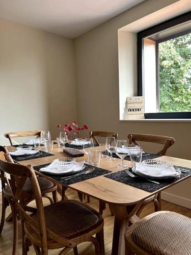 a wooden table with chairs and wine glasses on it at Gîte Bois Tordu - 3 chambres - proche Bourganeuf in Montboucher