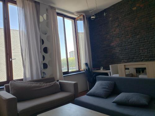 a living room with two couches and a brick wall at Appartement bien-être in Liège