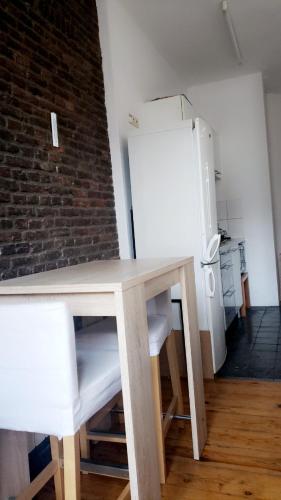 Appartement bien-être في لييج: طاولة وكراسي في مطبخ مع ثلاجة
