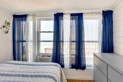 una camera da letto con tende blu, un letto e una finestra di Scenic Geneva Cottage with Lake Erie Beach Access! a Geneva