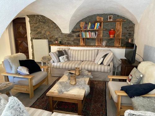 sala de estar con sofá, sillas y mesa en Les Chemines, en La Thuile
