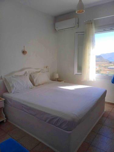a bedroom with a large bed with a window at Georgia Rooms Milos in Plaka Milou
