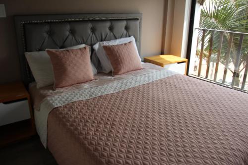 a bedroom with a bed with pink pillows and a window at Hotel Plaza El Santuario in Santuario