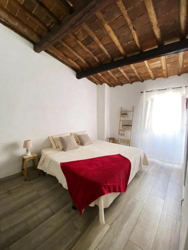 a bedroom with a bed with a red blanket on it at Casa da Moeda in Évora