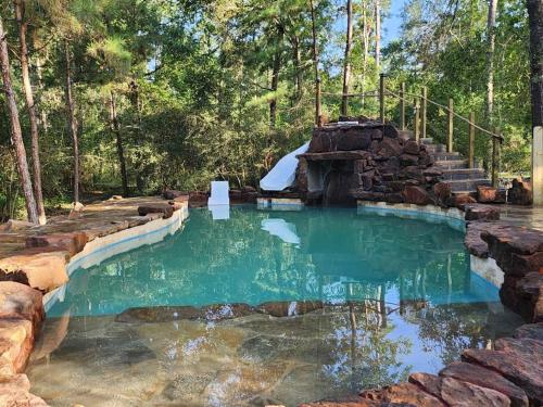a pool of water with a rock wall and stairs at Waterfront Treehouse in a Magical Forest in Waller