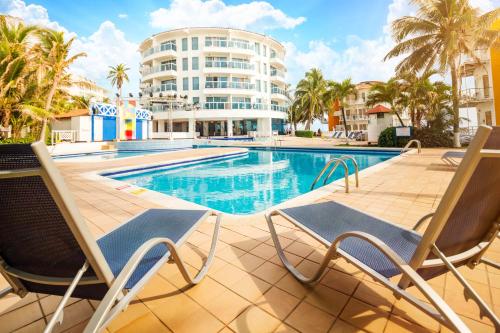 une piscine avec deux chaises et un bâtiment dans l'établissement Decameron Aquarium - All Inclusive, à San Andrés