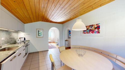 a kitchen with a wooden ceiling and a table at Haus Leibnitzer in St. Moritz