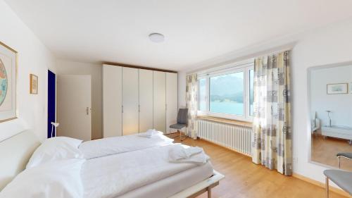 Un dormitorio con una gran cama blanca y una ventana en Haus Leibnitzer, en St. Moritz