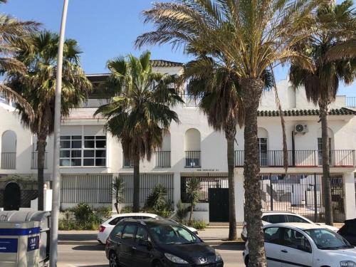 a parking lot with palm trees in front of a building at Dúplex en primera línea de playa 15 in Sanlúcar de Barrameda