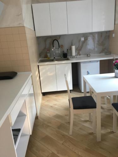 a kitchen with white cabinets and a white table and chairs at Pokoje gościnne Orlovo DT in Gdynia