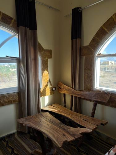 Habitación con mesa de madera y 2 ventanas. en People to People Hostel Siwa en Siwa