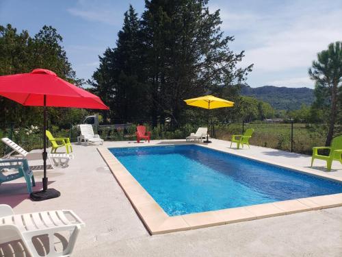 a swimming pool with chairs and umbrellas next to it at Le gîte du temps suspendu in Anduze