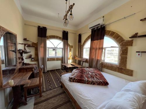 Schlafzimmer mit einem Bett, einem Schreibtisch und Fenstern in der Unterkunft People to People Hostel Siwa in Siwa