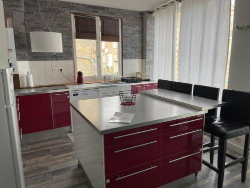 une cuisine avec des placards rouges et un comptoir blanc dans l'établissement L'appart de la plage du Casino, à Saint-Quay-Portrieux