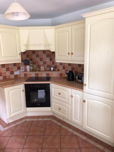 a kitchen with white cabinets and a black dishwasher at 2 Ballyloskey Road in Carndonagh